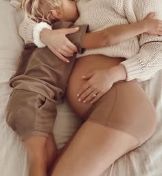 a woman laying on top of a bed next to a baby