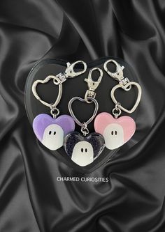 three heart shaped keychains with two faces on them, and one is in the shape of a ghost