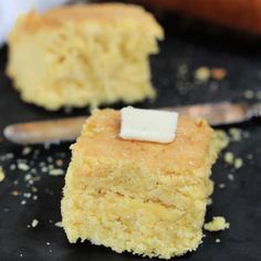 two pieces of cornbread sitting on top of a black surface next to a spoon