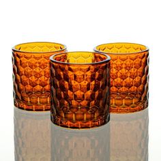 three orange glass tumblers sitting next to each other