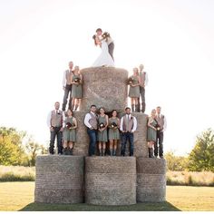 a bride and groom standing on top of hay bales with their bridal party