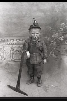 an old black and white photo of a little boy with a pipe in his mouth