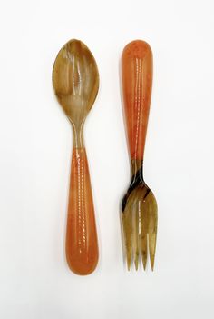 an orange and black fork and spoon on a white surface