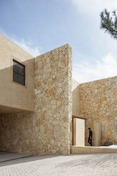 there is a man standing in front of a building that has stone walls and windows