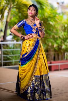 a woman in a yellow and blue dress posing for the camera with her hands on her hips