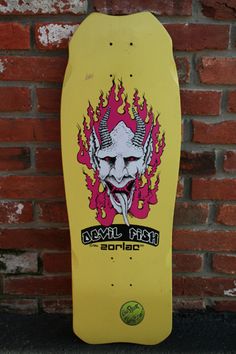 a yellow skateboard with an image of a demon on the back and flames coming out of it