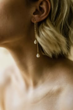 a close up of a person wearing earring with pearls on the end of their ears