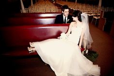 a bride and groom sitting on a red bench in front of rows of empty chairs