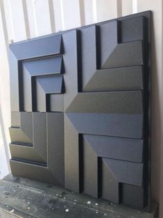 a large black sculpture sitting on top of a wooden table next to a white wall