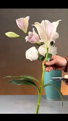 a person is cutting flowers in a vase