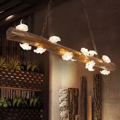 a large wooden light fixture hanging from the ceiling in a room with plants and other decorations