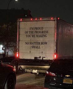 a truck with a message on the back driving down a street at night in traffic