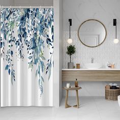 a bathroom with a shower curtain that has blue leaves on it and a mirror above the sink