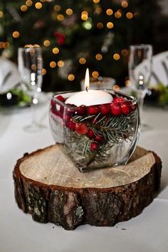 a candle that is sitting on top of a piece of wood in front of a christmas tree