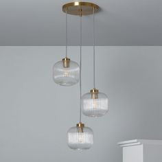 three clear glass globes hanging from a ceiling fixture in a room with white walls