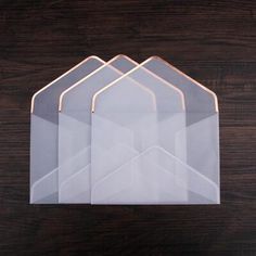 three clear envelopes sitting next to each other on a wooden table with a black background