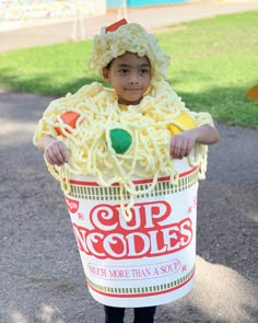 a young boy dressed up as a chicken noodle soup costume, holding a bucket with noodles in it