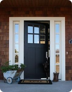 a black front door with two planters on the side and one potted plant next to it