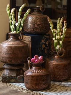 three vases with flowers in them sitting on a table next to an antique mirror