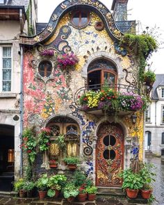 a building with many windows and flowers on the outside, along with potted plants