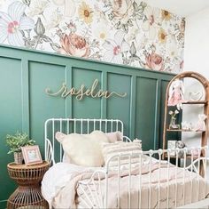 a white metal bed sitting in a bedroom next to a wall with flowers on it