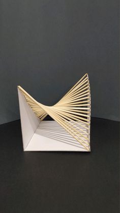 a sculpture made out of white paper on top of a black surface with lines in the middle