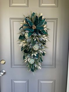 a wreath hanging on the front door of a house decorated with green and white ornaments