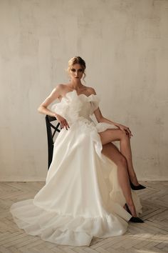 a woman in a white dress sitting on a chair