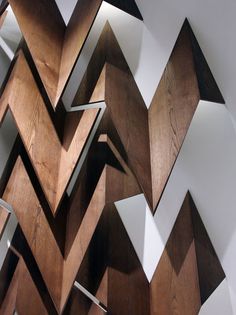 an abstract wooden sculpture with white walls and wood flooring in the shape of chevrons