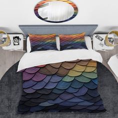 a bed covered in a rainbow colored comforter next to a mirror and two nightstands