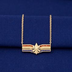 a gold necklace with an american flag design on the front and back, sitting on top of a blue cloth