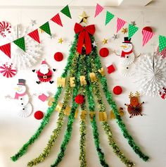 a christmas tree made out of green tinsel and paper garlands on a wall