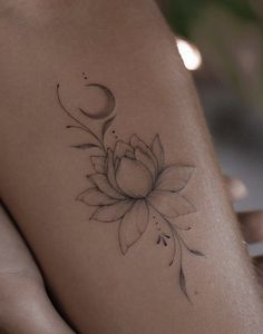 a woman's leg with a flower and crescent tattoo on her left side thigh