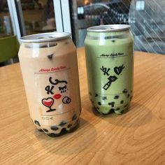 two soda cans sitting on top of a wooden table