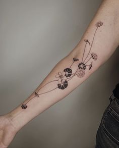 a woman's arm with flowers and leaves tattooed on the left side of her arm