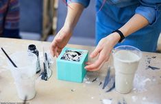 a woman is working on some crafting items at a table with paint and scissors