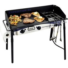 an outdoor gas grill with various foods cooking on the burner and side burners