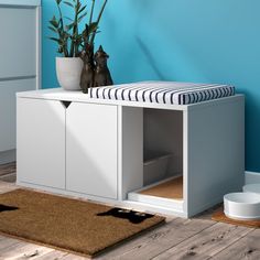 a white cabinet with two cats sitting on it's top shelf next to a potted plant