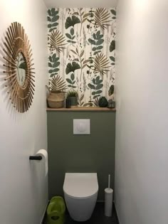 a bathroom with a toilet, mirror and plant wallpaper on the walls in it