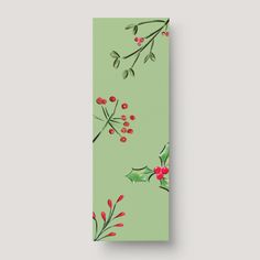 a green christmas bookmark with holly and berries on it, against a gray background