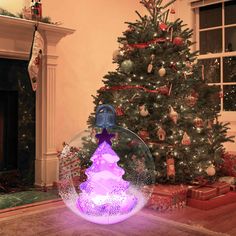 a christmas tree in a snow globe on the floor next to a fire place and fireplace