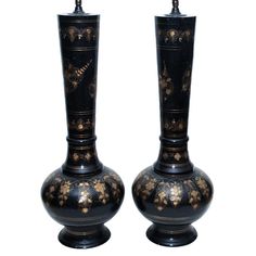 two black vases with gold designs on them