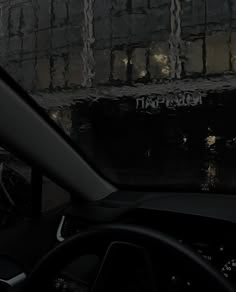 the interior of a car with graffiti on the wall behind it and steering wheel in view