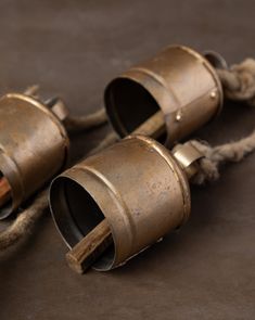 two old metal cups sitting on top of a brown floor next to ropes and twine