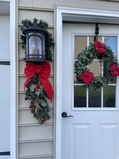 two christmas wreaths hanging on the front door of a house, one with a red bow