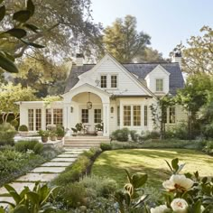 a white house surrounded by greenery and flowers