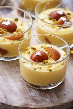 four desserts in small glass dishes on a wooden table