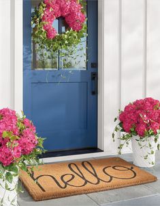 pink flowers are in front of a blue door with the word hello written on it