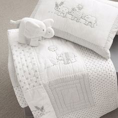 a white bed with an elephant on it and two pillows in the corner next to each other