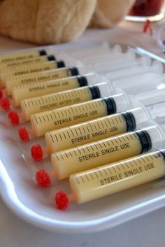 several syringes are lined up on a tray next to a teddy bear and other medical supplies